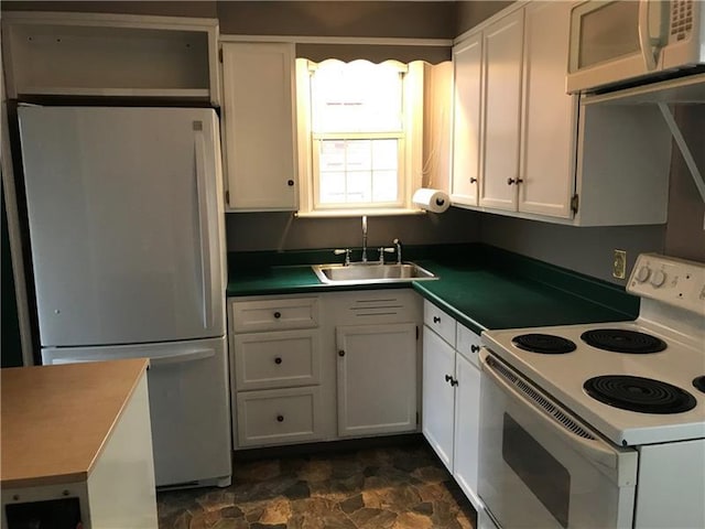 kitchen featuring white cabinets, white appliances, dark tile flooring, and sink