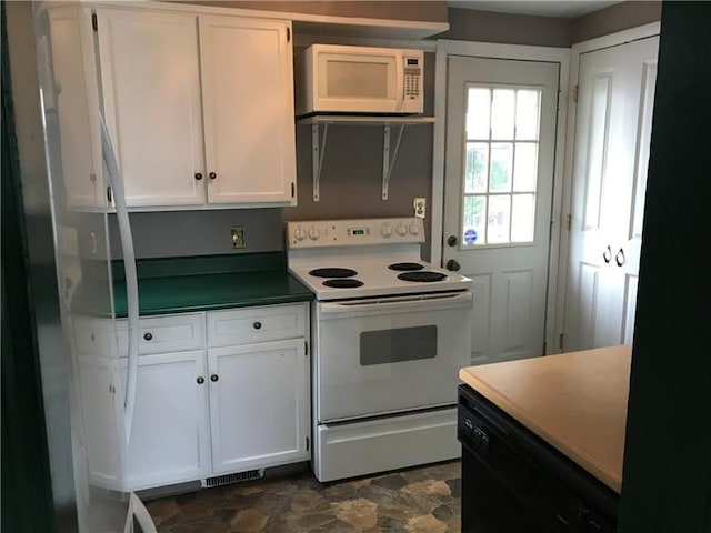 kitchen featuring white appliances, white cabinetry, and dark tile flooring