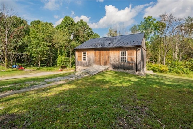 rear view of house featuring an outdoor structure and a yard