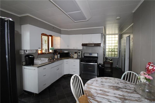 kitchen featuring black refrigerator, dark tile flooring, stainless steel range oven, sink, and white cabinetry