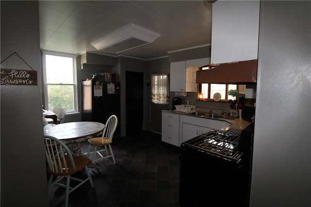 kitchen featuring range, dark tile floors, sink, white cabinets, and black fridge