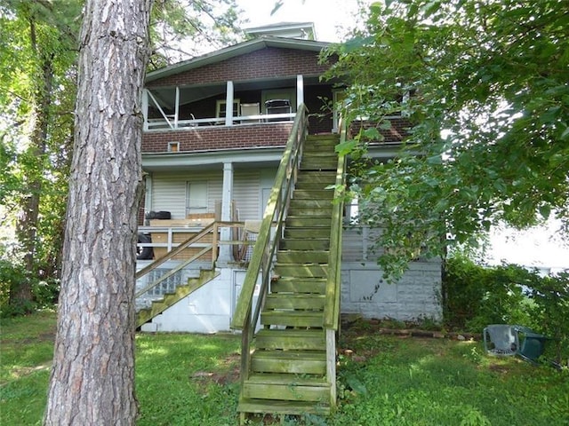 rear view of property featuring a balcony and a lawn