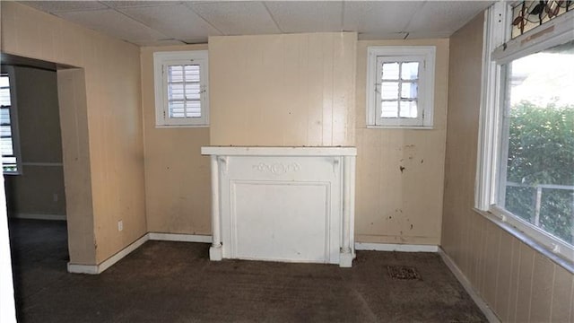 interior space with a paneled ceiling and dark carpet