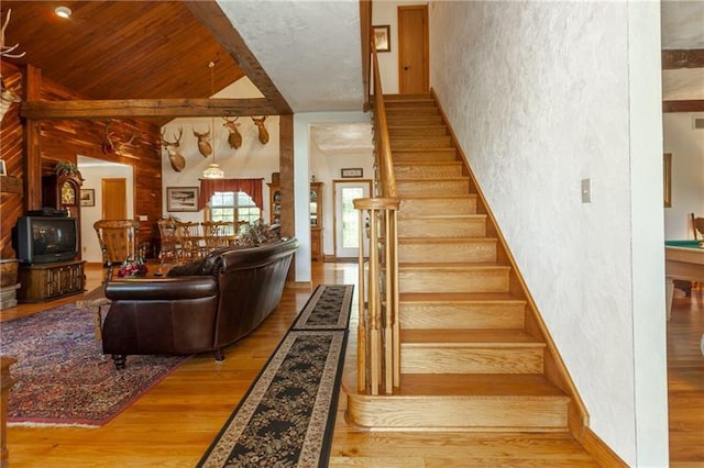 stairs with light hardwood / wood-style floors, a wood stove, and wood ceiling