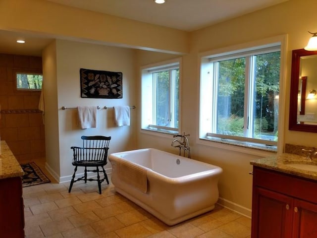 bathroom featuring plenty of natural light, a tub, vanity, and tile flooring