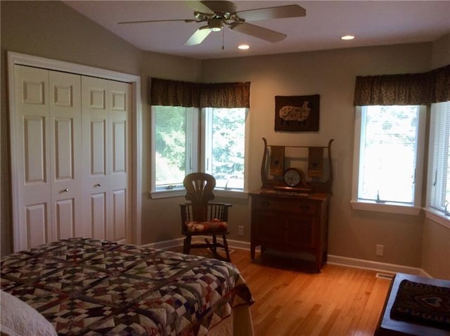 bedroom featuring multiple windows, a closet, ceiling fan, and light wood-type flooring