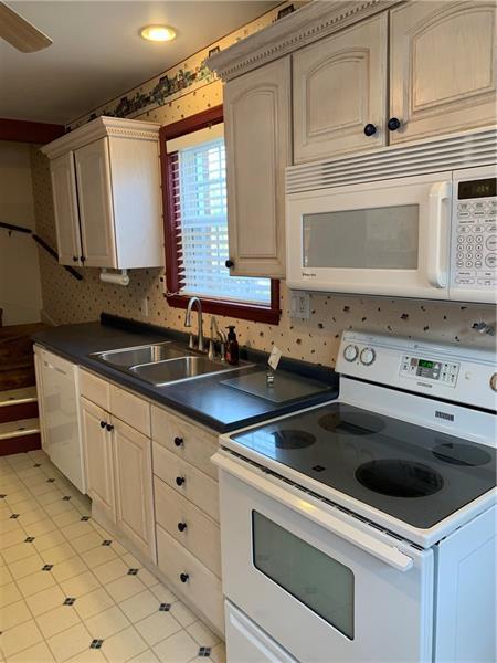 kitchen with light tile floors, ceiling fan, white appliances, backsplash, and sink