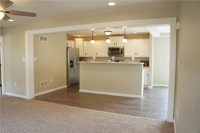 kitchen with pendant lighting, ceiling fan, a kitchen island, white cabinets, and appliances with stainless steel finishes