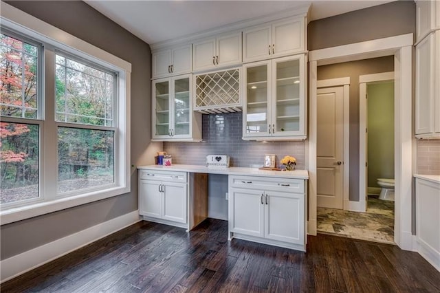 bar with backsplash, dark hardwood / wood-style flooring, and white cabinetry