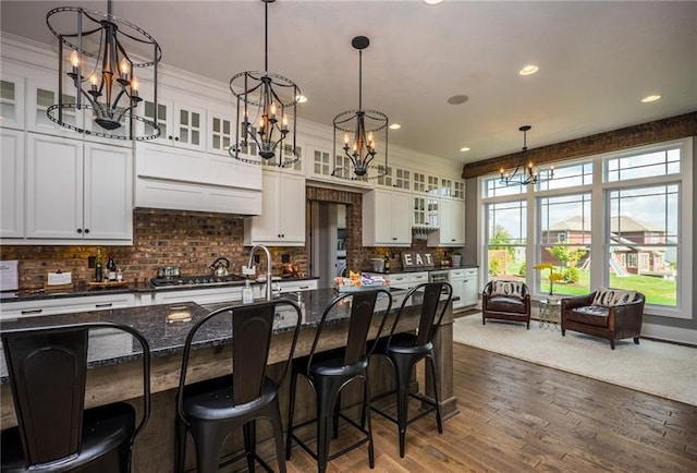 kitchen featuring white cabinets, a breakfast bar area, hardwood / wood-style floors, and plenty of natural light