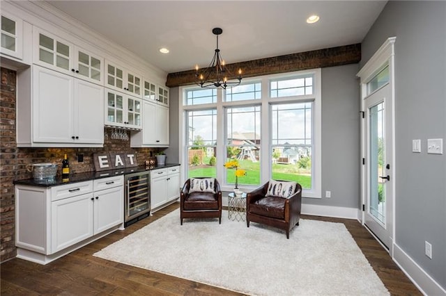 living area with plenty of natural light, beverage cooler, dark wood-type flooring, and a notable chandelier