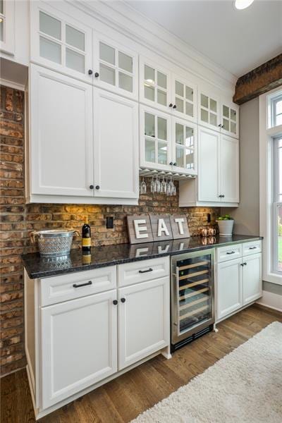 bar featuring beverage cooler, white cabinetry, plenty of natural light, and dark wood-type flooring