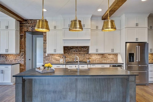 kitchen featuring a center island with sink, high quality fridge, and beam ceiling