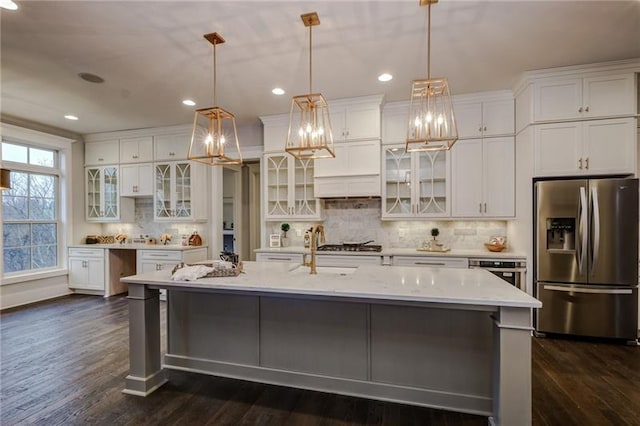 kitchen with appliances with stainless steel finishes, a kitchen island with sink, white cabinets, and dark hardwood / wood-style flooring