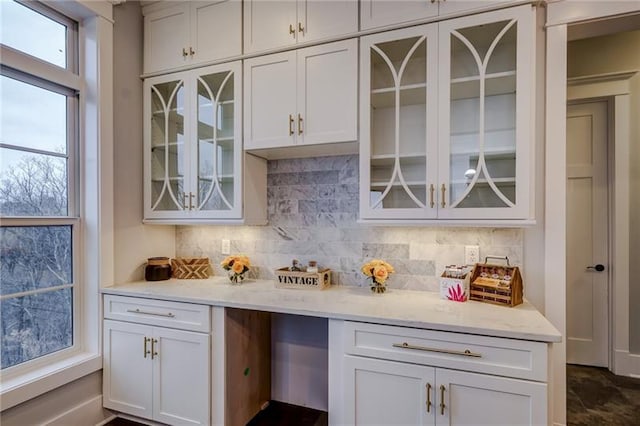 kitchen featuring light stone countertops, tasteful backsplash, white cabinetry, and dark tile flooring