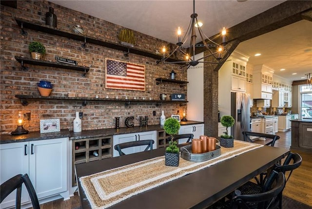 bar featuring stainless steel fridge, brick wall, white cabinets, a chandelier, and dark hardwood / wood-style flooring