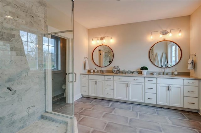 bathroom with double sink vanity, toilet, tile flooring, and a shower with shower door