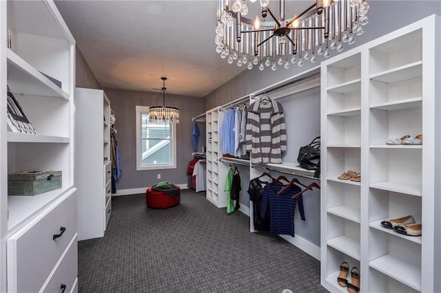 walk in closet with dark carpet and a notable chandelier