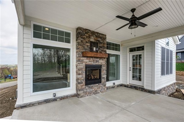 view of terrace with ceiling fan and an outdoor stone fireplace