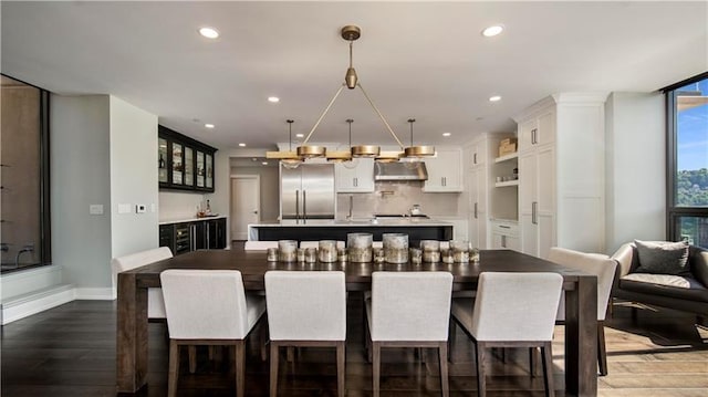 kitchen featuring a kitchen breakfast bar, a kitchen island, white cabinets, wall chimney range hood, and stainless steel built in fridge