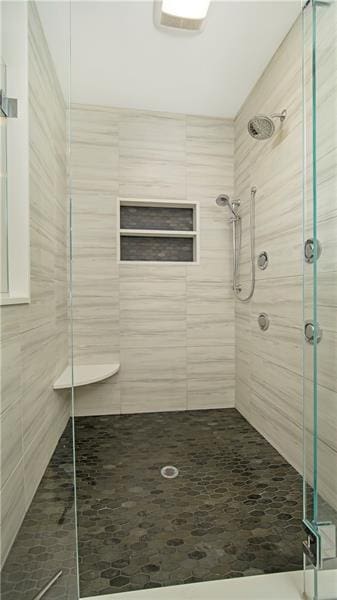 bathroom featuring a shower with shower door and tile walls