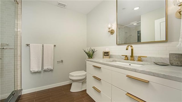 bathroom with an enclosed shower, vanity, backsplash, tile flooring, and toilet