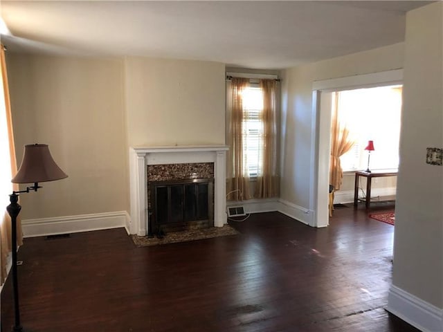 unfurnished living room featuring a premium fireplace, dark hardwood / wood-style floors, and plenty of natural light