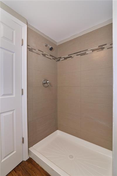 bathroom with a tile shower and hardwood / wood-style flooring