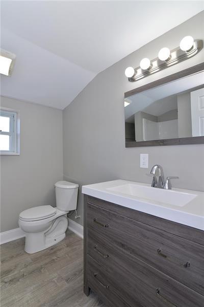 bathroom featuring vaulted ceiling, vanity, wood-type flooring, and toilet