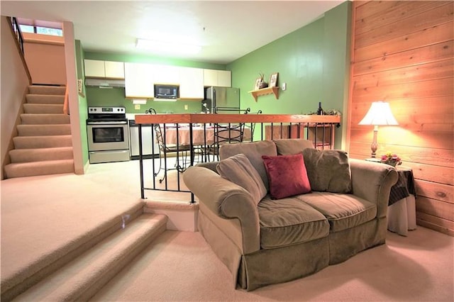 living room featuring wooden walls and light colored carpet