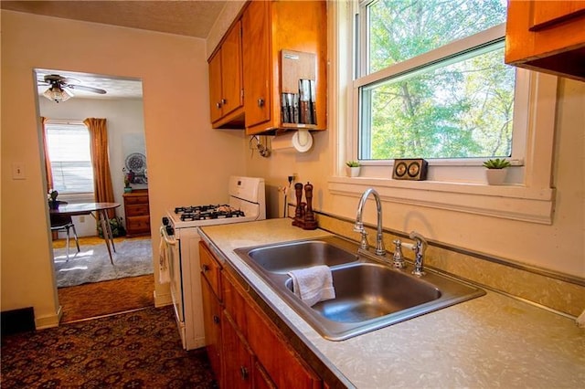 kitchen featuring ceiling fan, white gas stove, and sink