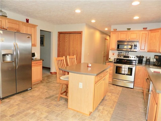 kitchen featuring appliances with stainless steel finishes, a center island, a breakfast bar area, and light tile floors