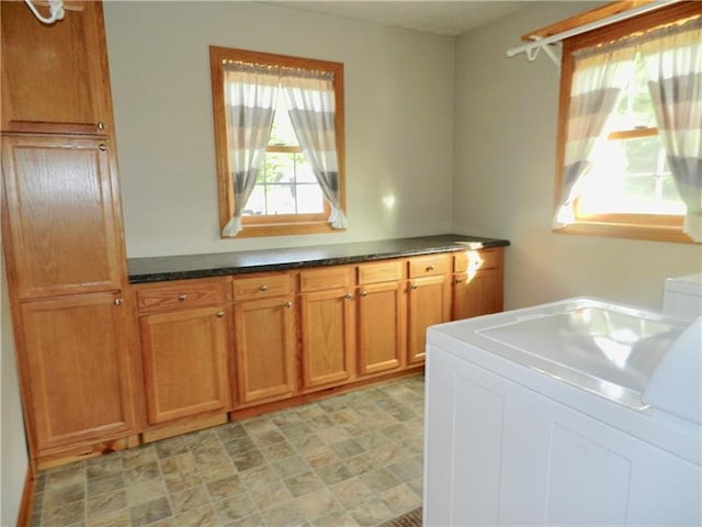 clothes washing area with light tile floors, cabinets, and washer / dryer