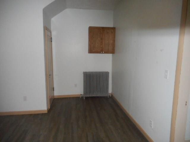 corridor with dark wood-type flooring and radiator