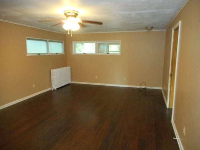 unfurnished room with radiator, crown molding, ceiling fan, and dark hardwood / wood-style flooring