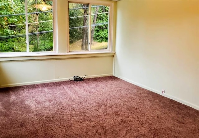 empty room featuring dark carpet and plenty of natural light