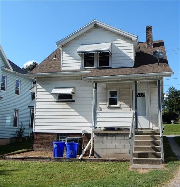 rear view of property featuring a lawn