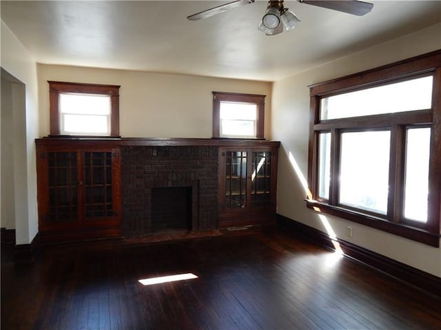 unfurnished living room featuring a brick fireplace, ceiling fan, and dark wood-type flooring