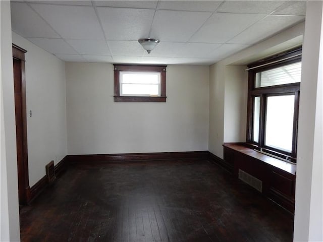 unfurnished room with dark hardwood / wood-style floors and a drop ceiling