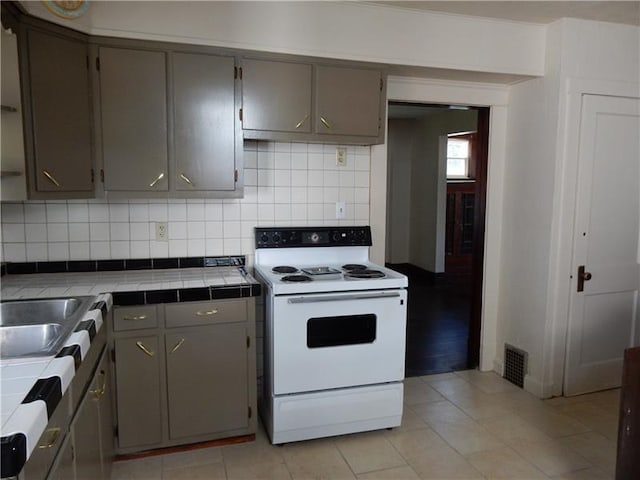 kitchen with backsplash, tile counters, electric range, and light hardwood / wood-style flooring