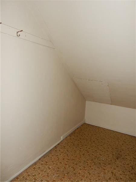 bonus room with lofted ceiling and carpet flooring