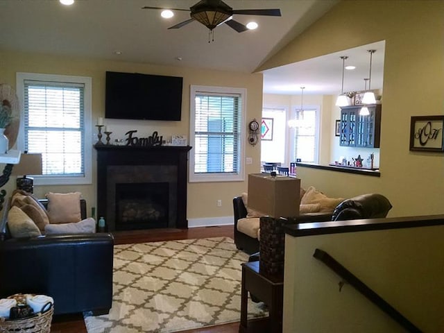 living room with vaulted ceiling, ceiling fan with notable chandelier, and hardwood / wood-style flooring