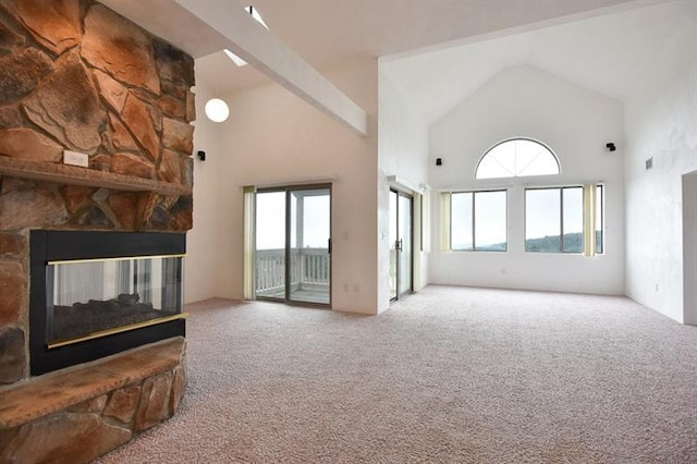 living room with plenty of natural light, a stone fireplace, high vaulted ceiling, and light carpet