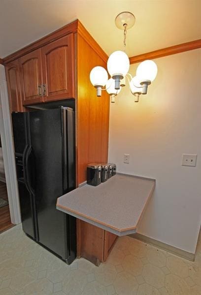 kitchen with an inviting chandelier, ornamental molding, black fridge with ice dispenser, and light tile floors