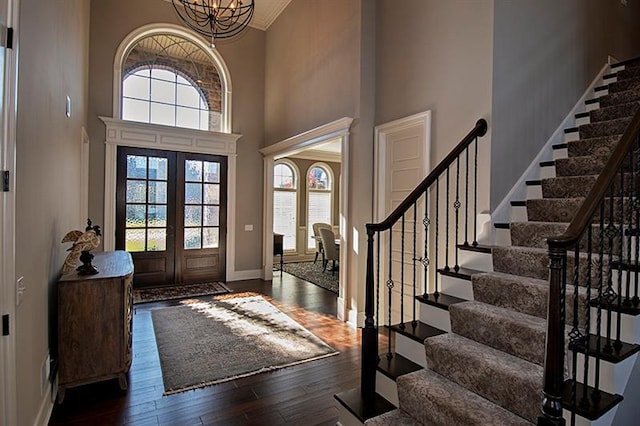 entryway featuring dark hardwood / wood-style flooring, an inviting chandelier, french doors, and a towering ceiling