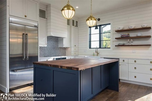 kitchen with wooden counters, dark wood-type flooring, built in refrigerator, and a kitchen island