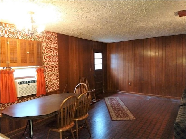 unfurnished dining area with an inviting chandelier, a textured ceiling, and wood walls