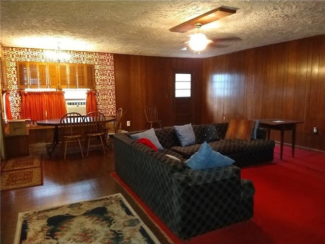 living room with ceiling fan, wood walls, and a textured ceiling