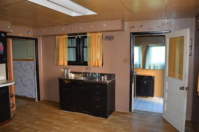 kitchen with sink, a paneled ceiling, and light hardwood / wood-style floors