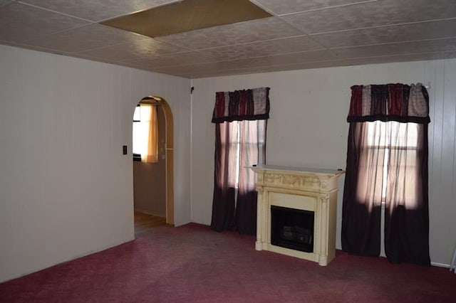 unfurnished living room with dark colored carpet and plenty of natural light